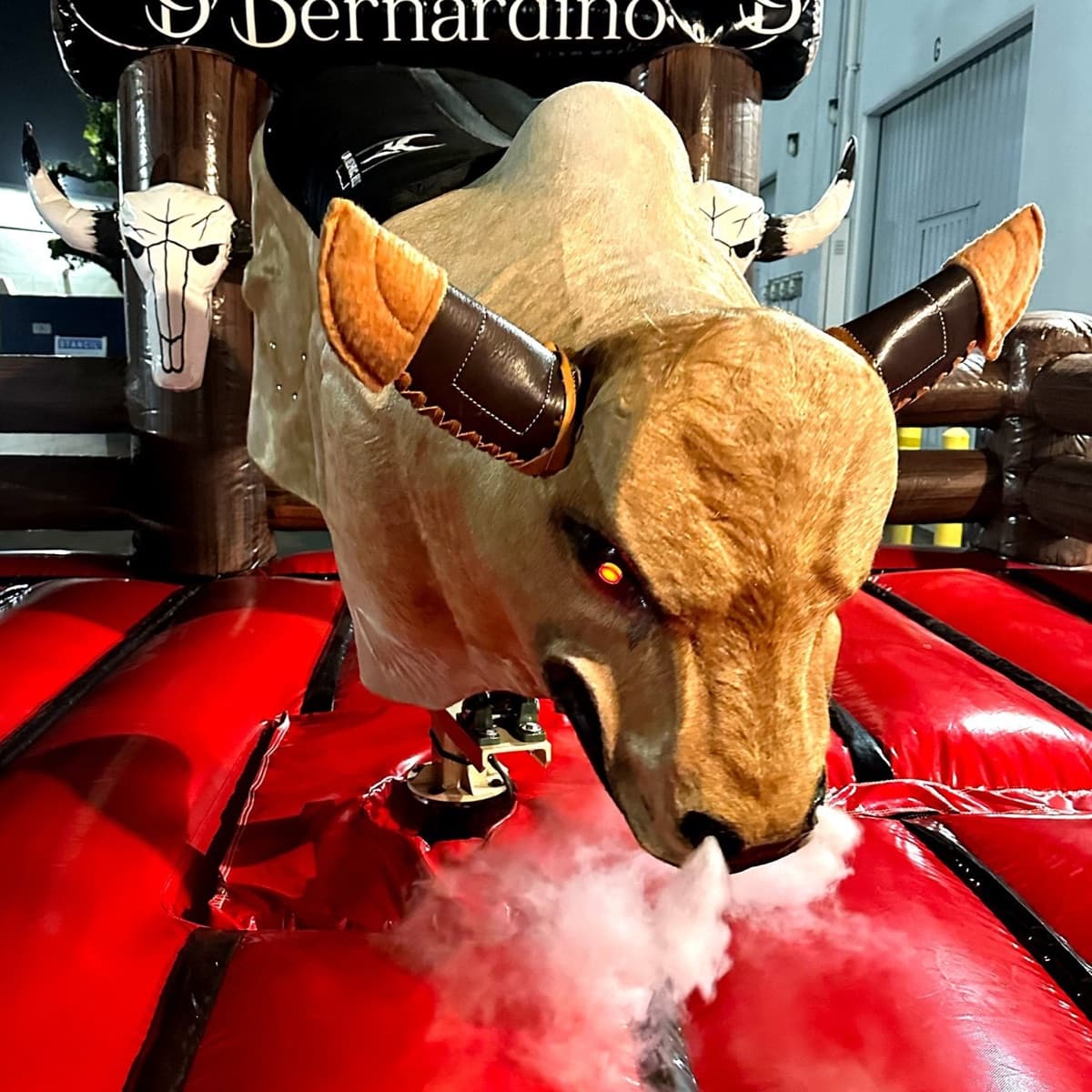 Premium package — tan mechanical bull with leather-wrapped horns blowing smoke on a red mattress